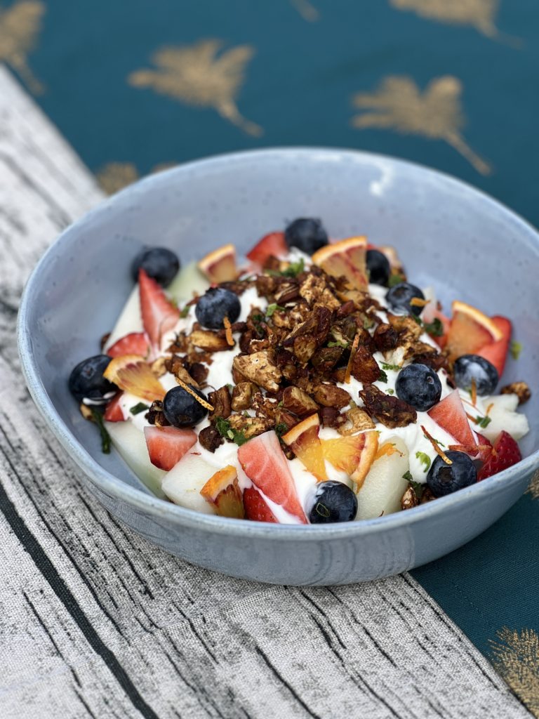 Bowl of Passover granola sat on top of a bed of fruit and yogurt