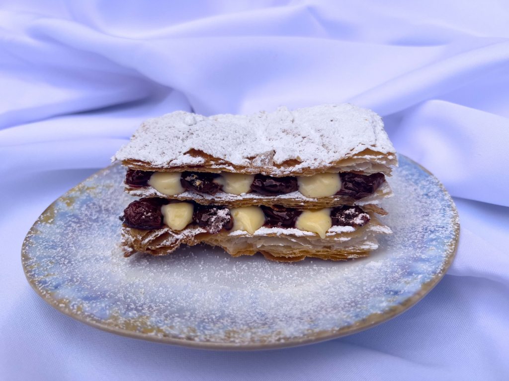 Cherry Millefeuille photographed on a white and blue plate and white tablecloth