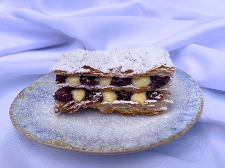 Cherry Millefeuille photographed on a white and blue plate and white tablecloth